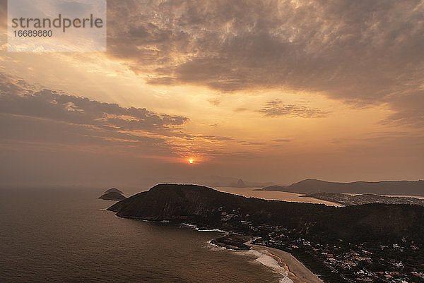 Schöner Blick auf den Sonnenuntergang von der Hügelspitze auf das Meer  den Strand und die orangefarbenen Wolken