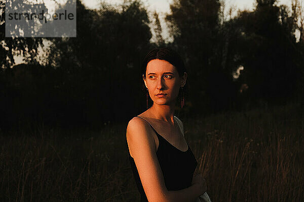 Junge erwachsene Frau im Kleid posiert bei Sonnenuntergang. Low key portrait of