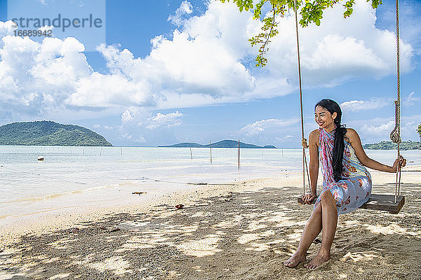 schöne Frau auf einer Schaukel am Strand in Phuket sitzend