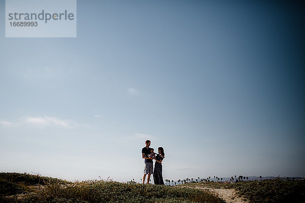 Mutter und Vater halten junge Sonne am Strand  Silhouette