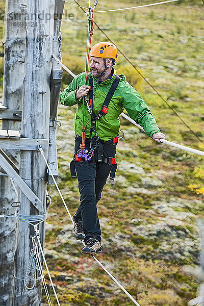 Mann balanciert auf einem Hochseil-Hindernisparcours in Island
