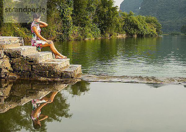 schöne Frau  die am Fluss Li in Yangshuo sitzt