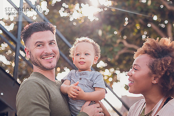 Vater hält kleinen Jungen und Mutter schaut auf das Baby