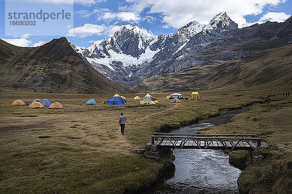 Eine Person wandert zu den Zelten eines Camps in der Cordillera Huayhuash