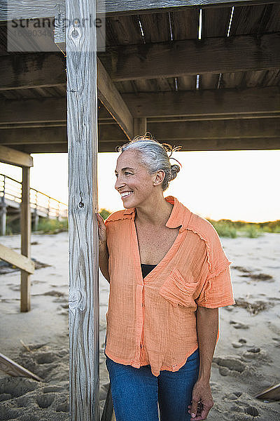 Porträt einer grauhaarigen Frau am Strand bei Sonnenuntergang