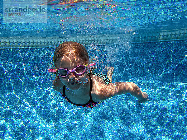 Mädchen schwimmt unter Wasser mit Schwimmbrille