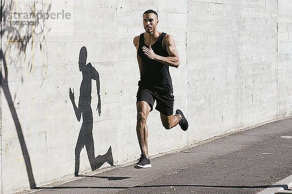 Afroamerikanischer Sportler läuft in voller Länge gegen eine Betonwand