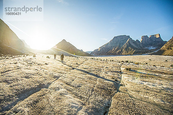 Rucksacktouristen überqueren den Gletscher bei Sonnenuntergang.