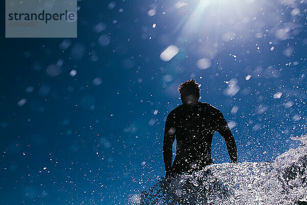Surfer in Aktion vor einem blauen Himmel voller Wassertröpfchen