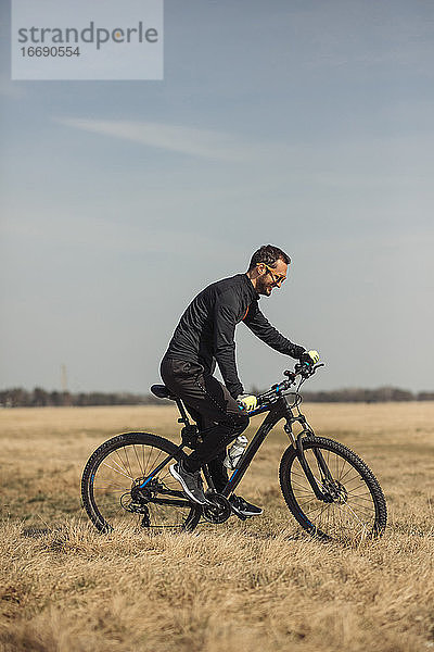 Junger Mann fährt mit dem Fahrrad auf einer Wiese