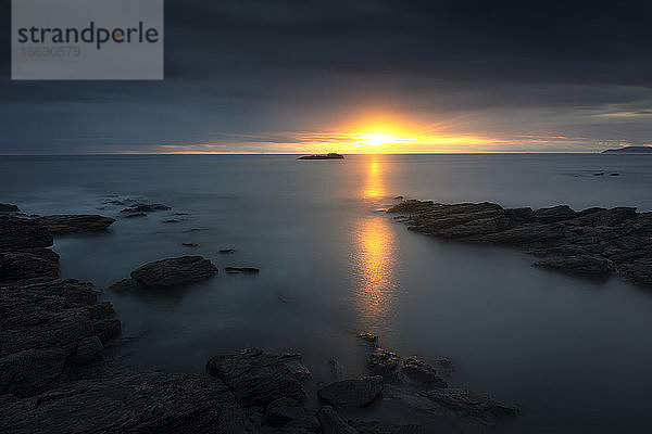 Spektakulärer Sonnenuntergang mit den letzten Strahlen der Sonne über dem Meer