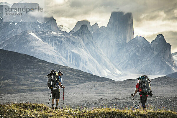 Zwei Bergsteiger wandern zum Mount Asgard am Akshayak Pass auf Baffin Island.