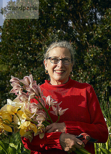 Ältere Frau hält Blumenstrauß mit frischen Schnittblumen in ihrem Garten