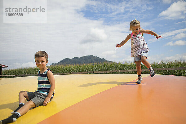 Bruder und Schwester genießen die Zeit im Freien und springen auf dem Trampolin.