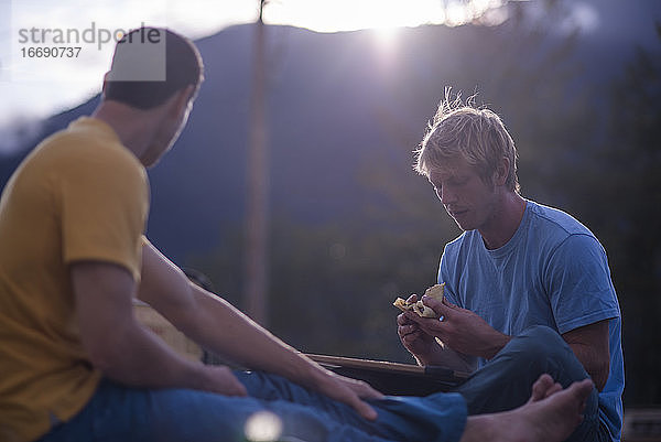 Zwei Männer essen Crêpes bei Sonnenuntergang auf einem Dach im Freien Squamish Kanada