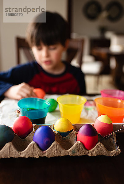 Bunte Ostereier mit einem Jungen  der sie im Hintergrund färbt.