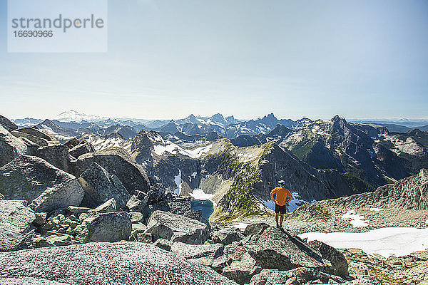 Mann steht auf einem Felsbrocken mit Blick auf die Berge  Mount Baker.