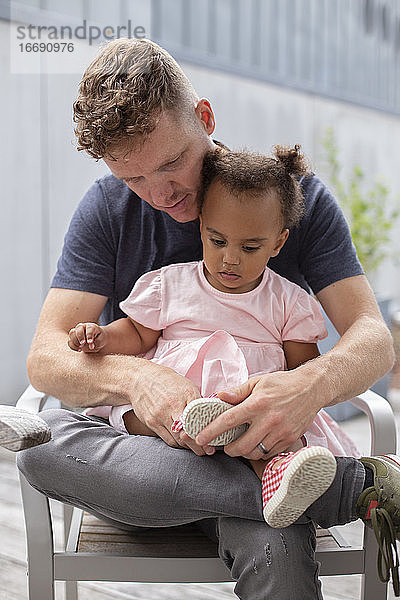 Ein Vater hilft seiner Tochter beim Anziehen ihrer Schuhe