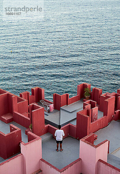 Junger lateinamerikanischer Mann meditativ in 'Muralla Roja' aus Calpe  Spanien