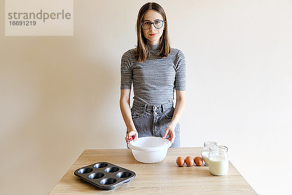 Frau in T-Shirt und Jeans bereitet in ihrer Küche hausgemachte Cupcakes zu