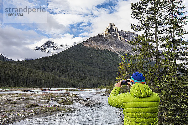 Mann in grüner Jacke fotografiert den Alexandra Mountain  Banff  Kanada