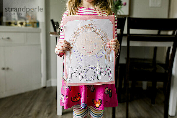 Junges Mädchen mit einer Zeichnung  die sie zum Muttertag von ihrer Mutter angefertigt hat