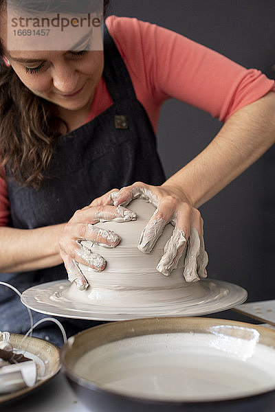 Junge Frau bearbeitet Ton in einem Keramikstudio