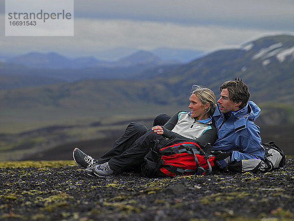 Wanderndes Paar entspannt sich am Berghang in Island