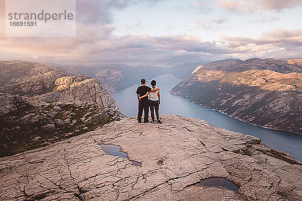 Paar steht bei Sonnenuntergang auf der Klippe am Preikestolen  Norwegen
