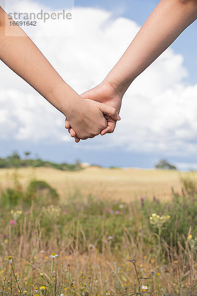 Helfende Hand zwischen zwei Brüdern im Hintergrund des blauen Himmels  Familie