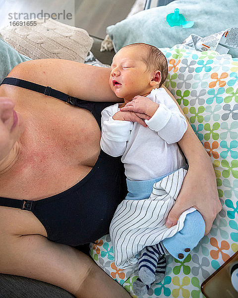 Neugeborenes Baby schläft friedlich in den Armen der Mutter.