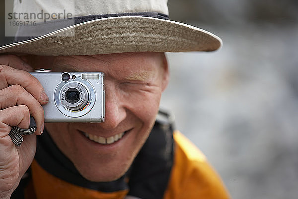 Mann  der in Grönland ein Foto mit einer digitalen Point-and-Shoot-Kamera macht