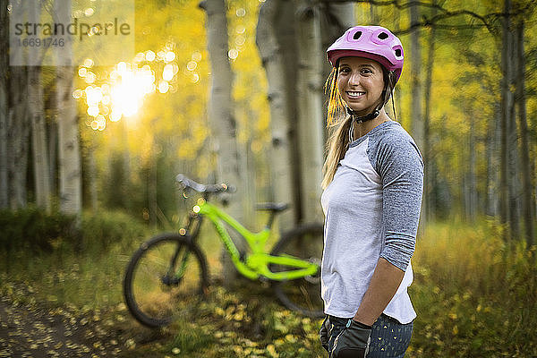 Porträt einer lächelnden Mountainbikerin im Wald