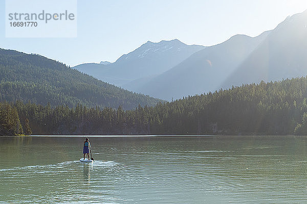 Schwangere Frau paddelt auf einem ruhigen Bergsee