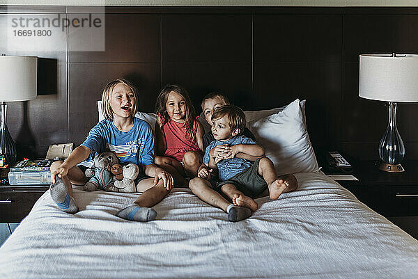 Geschwister sitzen und lachen auf dem Hotelbett im Urlaub in Palm Springs