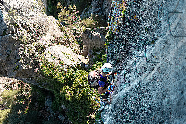 Konzept: Abenteuer. Frau mit Helm  Klettergurt und Rucksack. Walking down Eisentreppe in der Wand. tun Klettersteig in den Bergen.