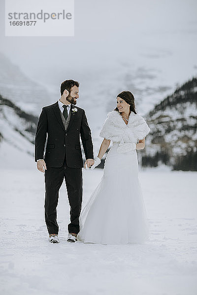 Braut und Bräutigam verliebt auf Eis auf gefrorenem See in den Bergen im Winter