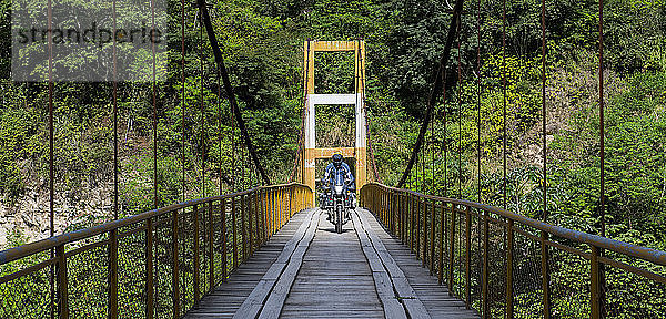 Mann mit Reisemotorrad auf Hängebrücke in Peru