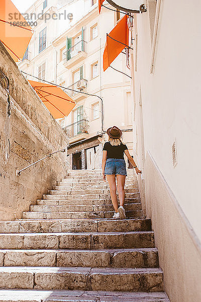 Rückenansicht einer abenteuerlustigen Reisenden  die eine Treppe hinaufgeht  auf Mallorca