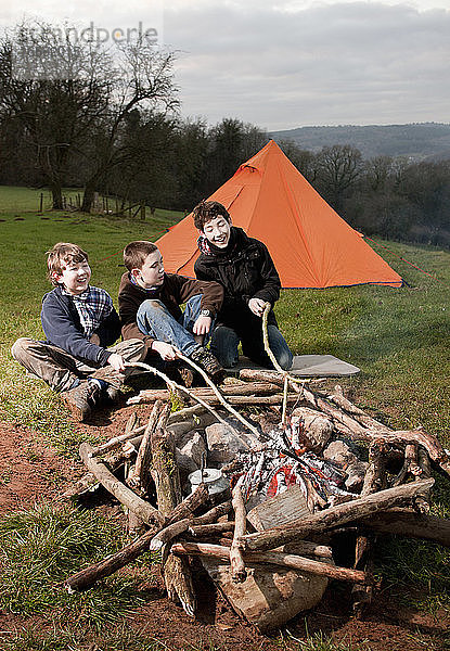 drei Jungen sitzen am Lagerfeuer in Südwales
