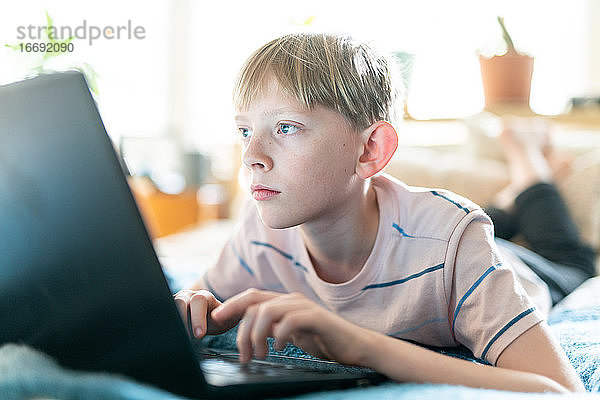 Close up Porträt von Teenager arbeiten am Laptop im Inneren auf hellen sonnigen Tag