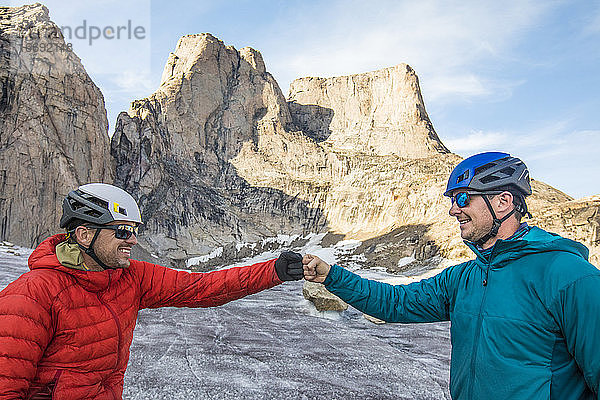Zwei Kletterer stoßen sich nach einer erfolgreichen Klettertour die Hände.