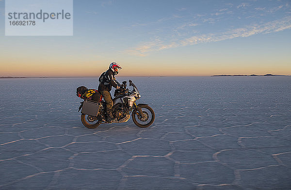 Ein Mann fährt mit seinem Reisemotorrad auf den Salinen von Uyuni in Bolivien