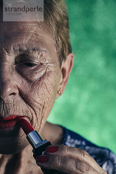 Reife Frau im Vordergrund malt ihre Lippen rot an