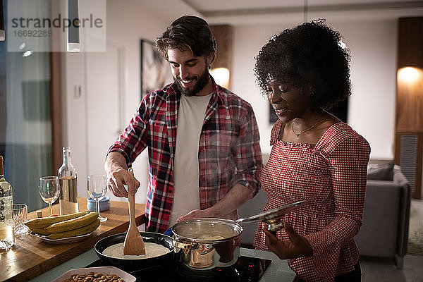 Unterschiedliches Paar bereitet romantisches Abendessen in der Küche vor