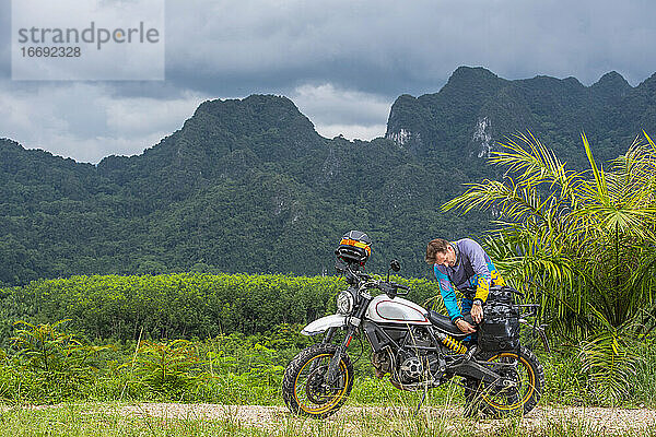 Mann packt sein Scrambler-Motorrad in den Bergen von Thailand