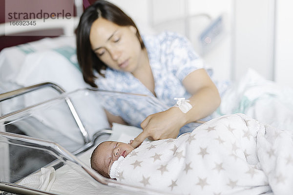 Mutter mit schlafendem neugeborenem Kind im Krankenhaus