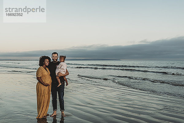 Porträt einer dreiköpfigen Familie  die am Strand lächelt