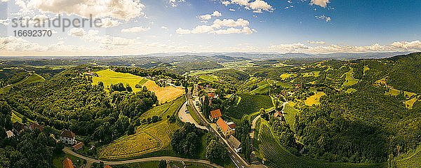 Luftbildpanorama von grünen Hügeln und Weinbergen mit Bergen im Hintergrund. Österreich Weinberge Landschaft in Kitzeck im Sausal