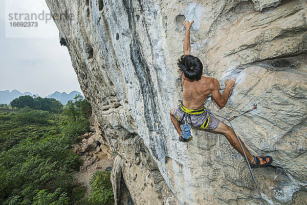 Mann beim Klettern auf dem Kalksteinfelsen Weißer Berg in Yangshuo
